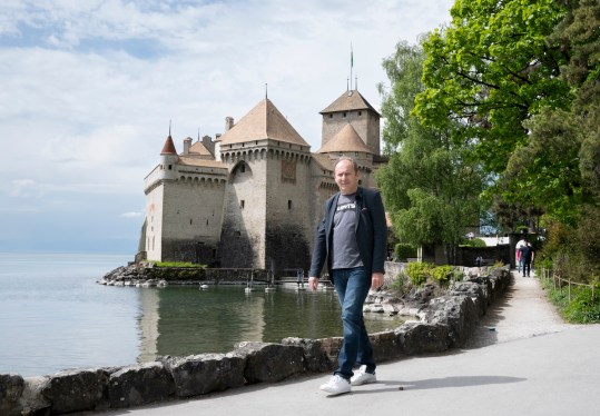 Man walking lakeside, castle in background