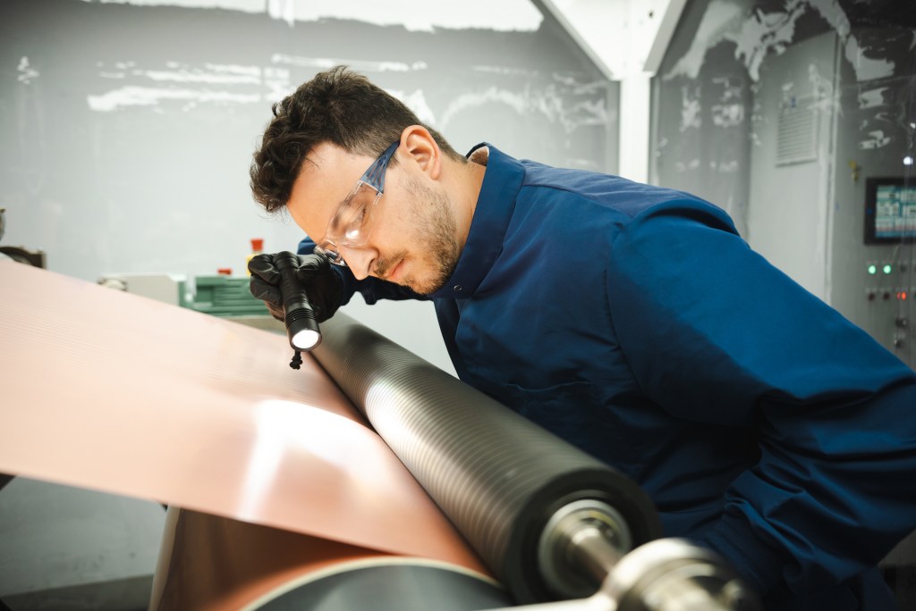 A worker examines copper at a Redwood Materials factory.