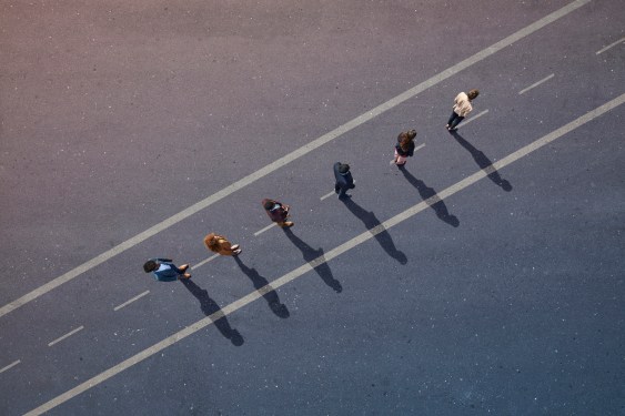 Group of business people moving down the dividing line of a highway, meant to symbolize regulation and compliance by toeing the line.