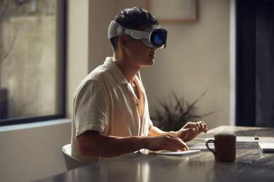 A person types on a keyboard while wearing an Apple Vision Pro headset.