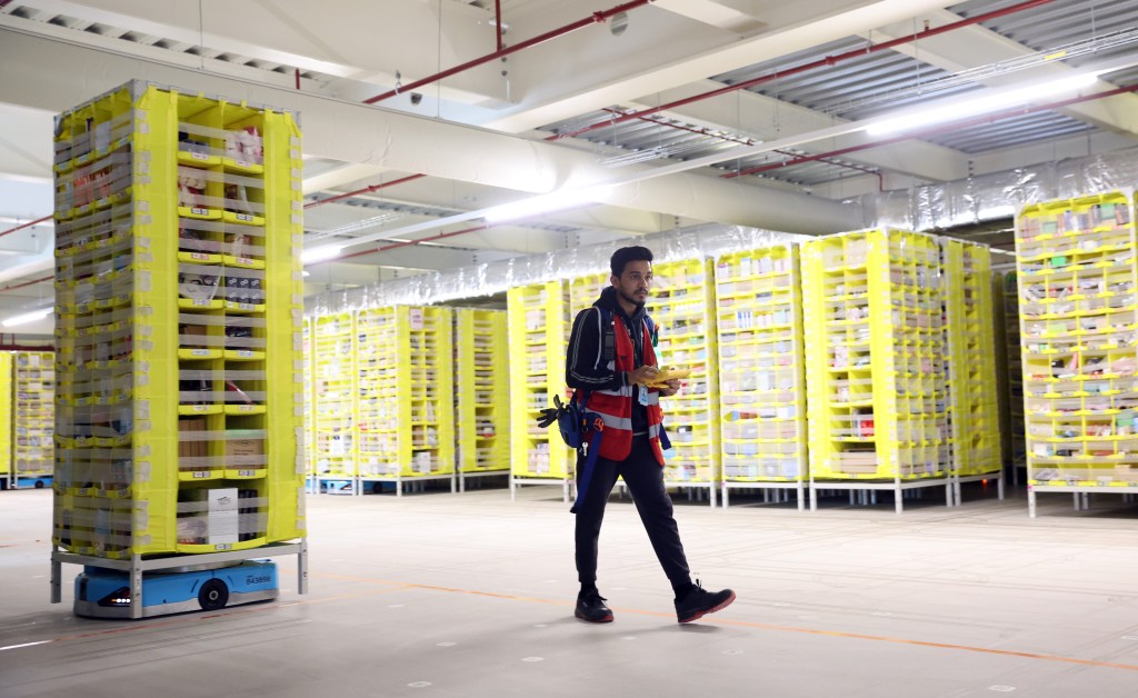 An Amazon employee checks the robotic warehouse at Amazon's Robotic Fulfillment Center on December 19, 2023 in Sutton Coldfield, England.