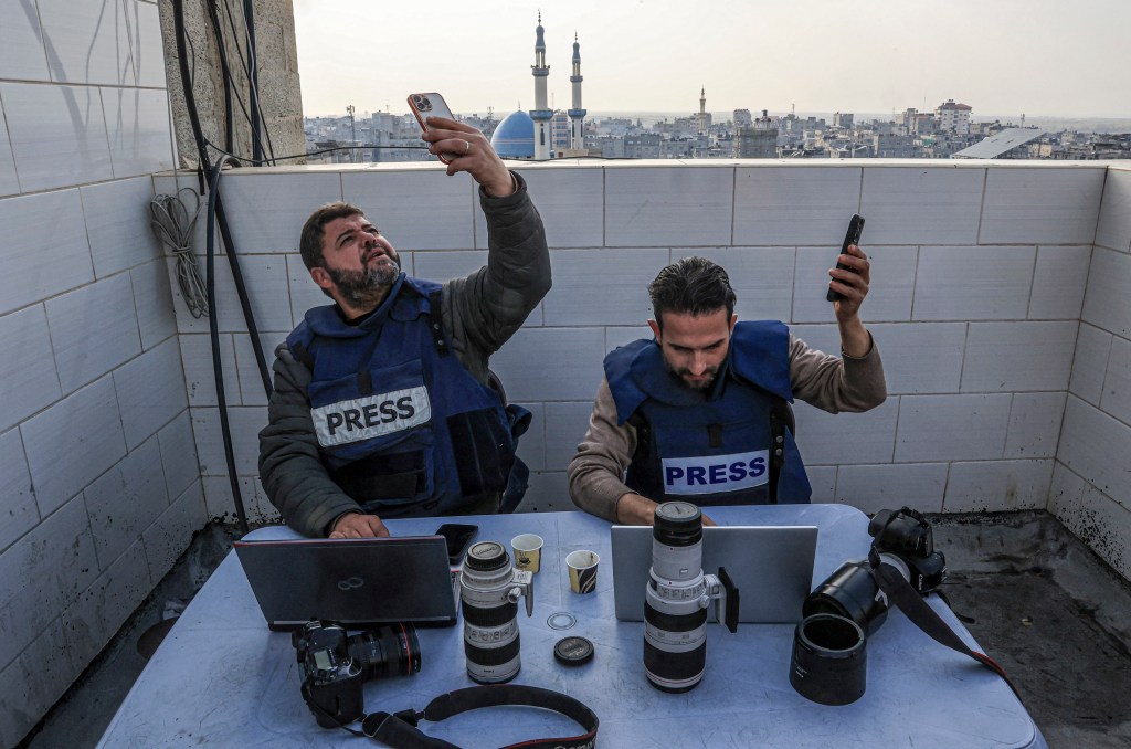 Palestinian journalists attempt to connect to the internet using their phones in Rafah on the southern Gaza Strip on December 27, 2023, amid continuing battles between Israel and the Palestinian militant group Hamas.