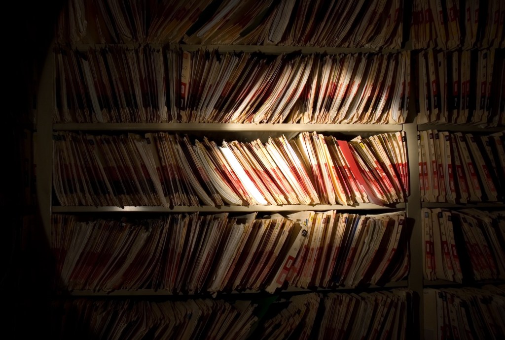 Flashlight beam shining on medical records in a dark room