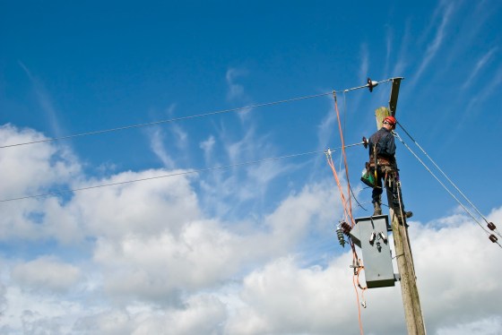 Utility worker repairing power lines under a blue sky