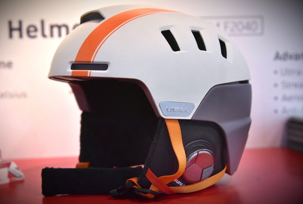 a Livall smart helmet in white with an orange stripe down the center with orange straps