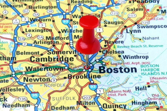 A red push pin pointing out Boston and its environs on a map.