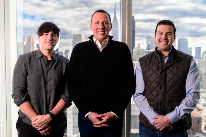 Evan Caron, Philip Krim, and Sharo Atmeh pose in front of the New York City skyline.