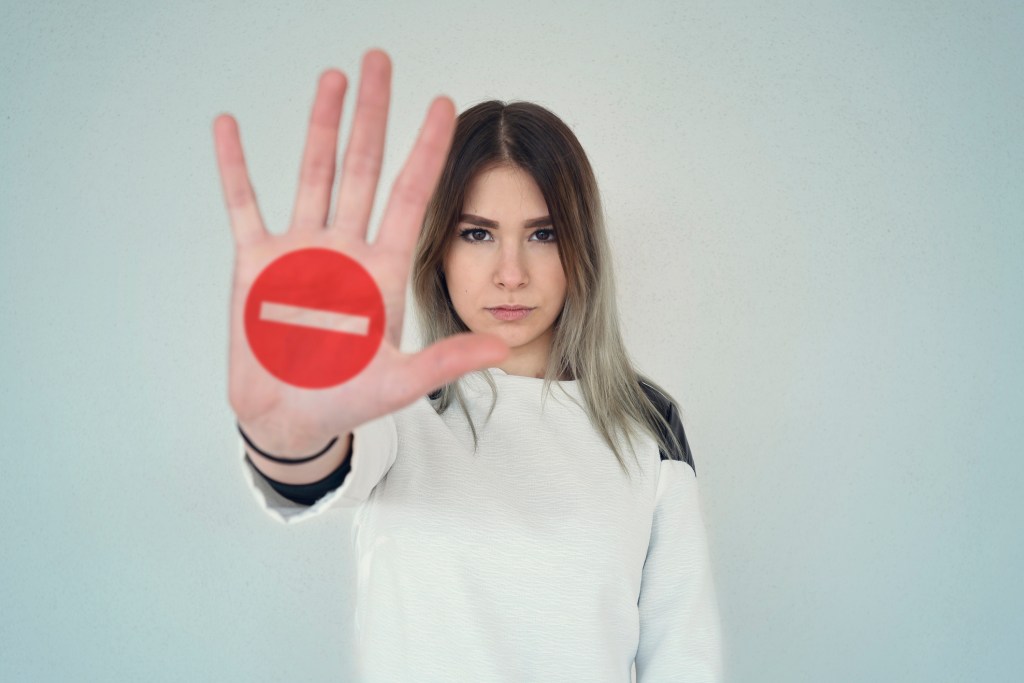 Woman holding hand out with stop sign on it.