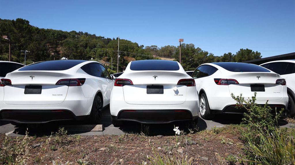 Brand new Tesla cars sit in a parking lot at a Tesla showroom.
