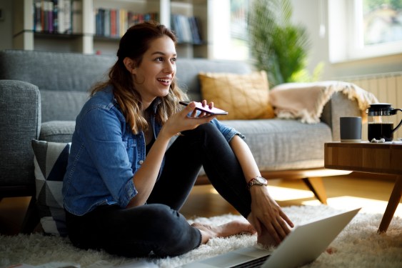 Young woman sitting on living room floor talking into mobile phone