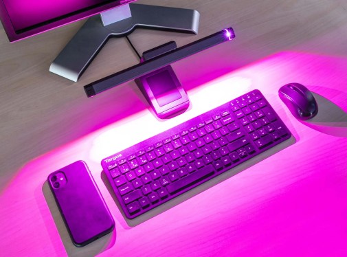 a photo of a purple lit-up computer display and keyboard on a computer desk