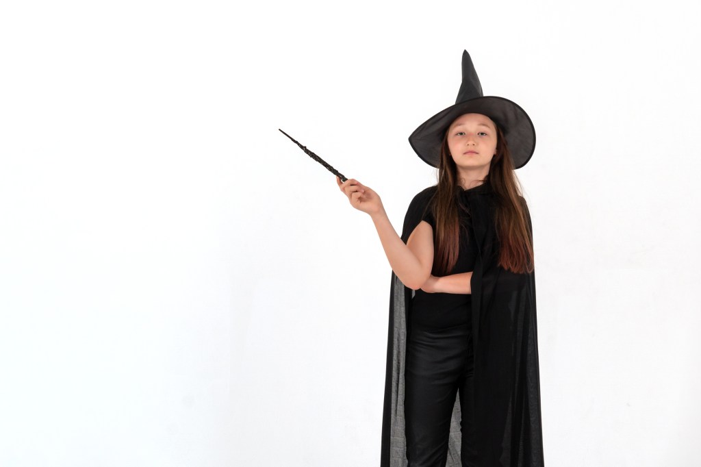 Girl in Harry Potter costume holding a magic wand.