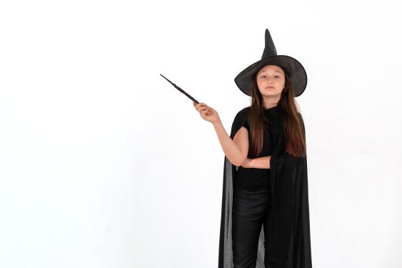Girl in Harry Potter costume holding a magic wand.