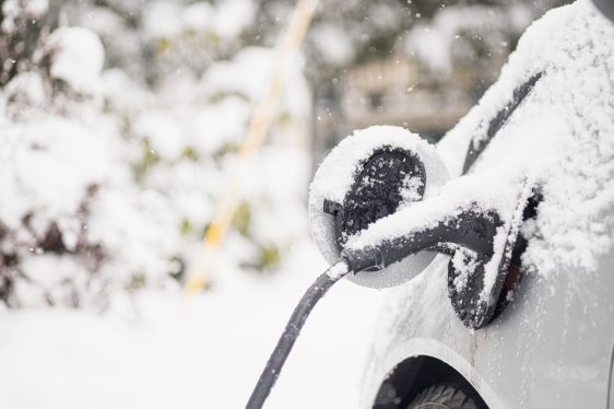 An electric vehicle charges in the snow.