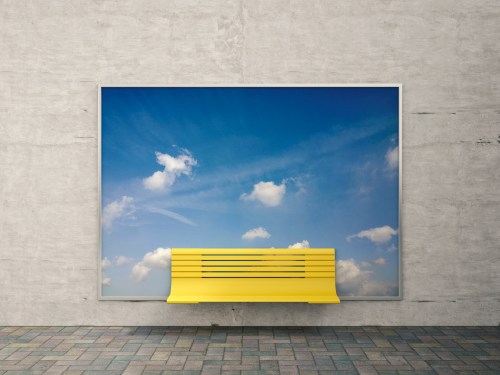 Yellow bench in front of billboard with sky and clouds