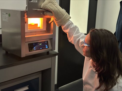 A scientist observes battery material production.