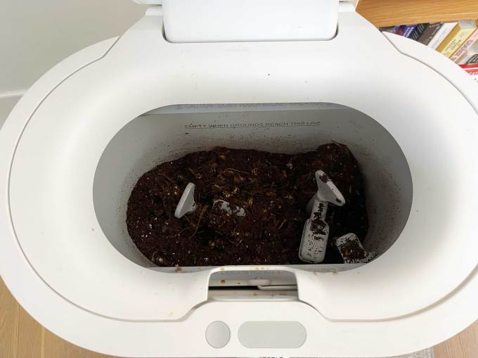 Mill food waste bin sits open with grounds inside.