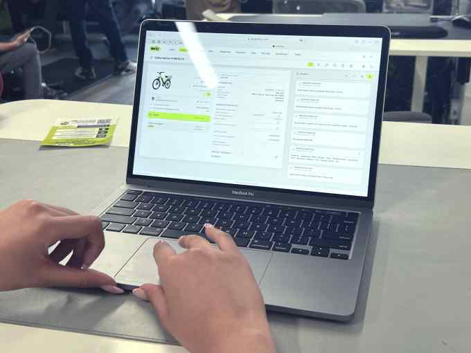 Hands on an open Apple laptop displaying Whizz's management software.