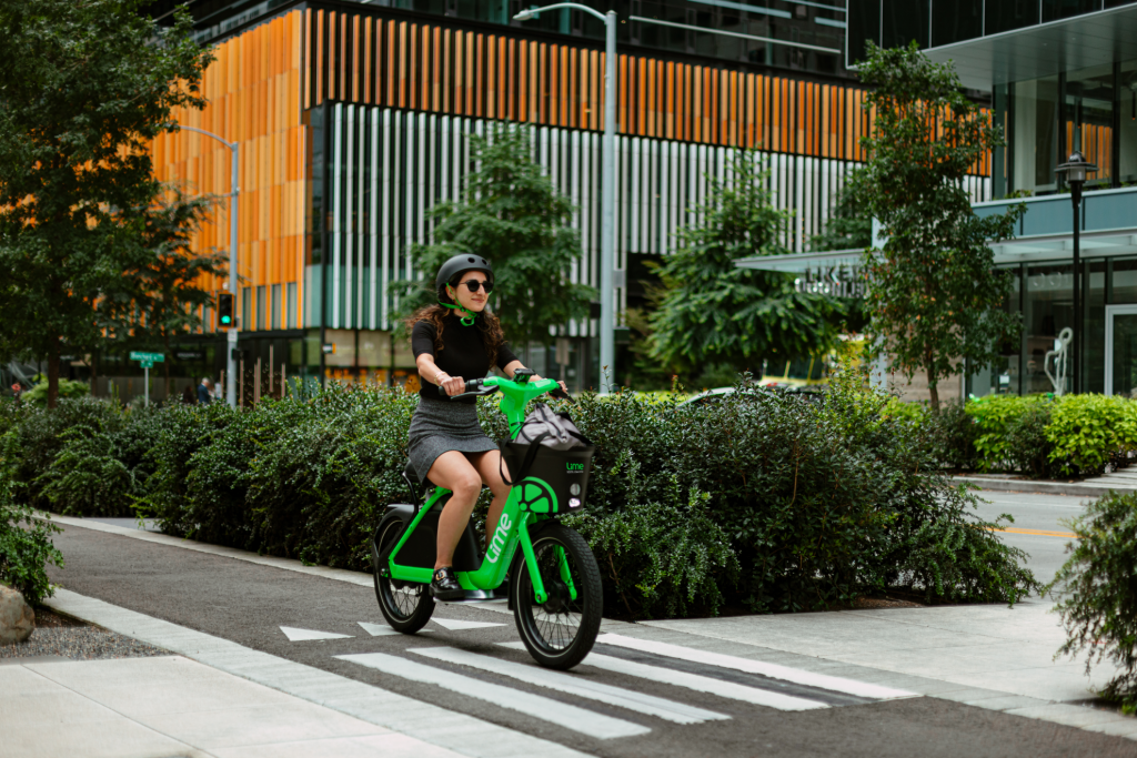 woman riding bright green e-bike across walkway in seattle