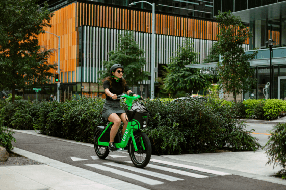 woman riding bright green e-bike across walkway in seattle
