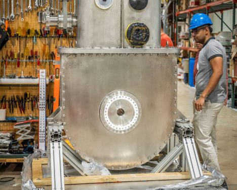 A scientist inspects a superconducting magnet for a fusion power experiment.