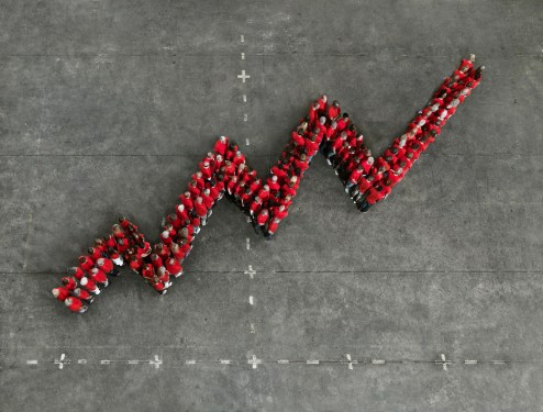 A crowd of people wearing red shirts, forming a graph shape. Photographed from above.