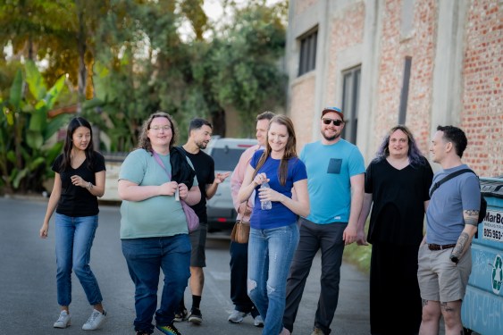 small group of young folks standing in a parking lot