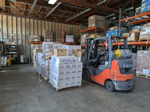 forklift parked next to pallets stacked with goods in warehouse