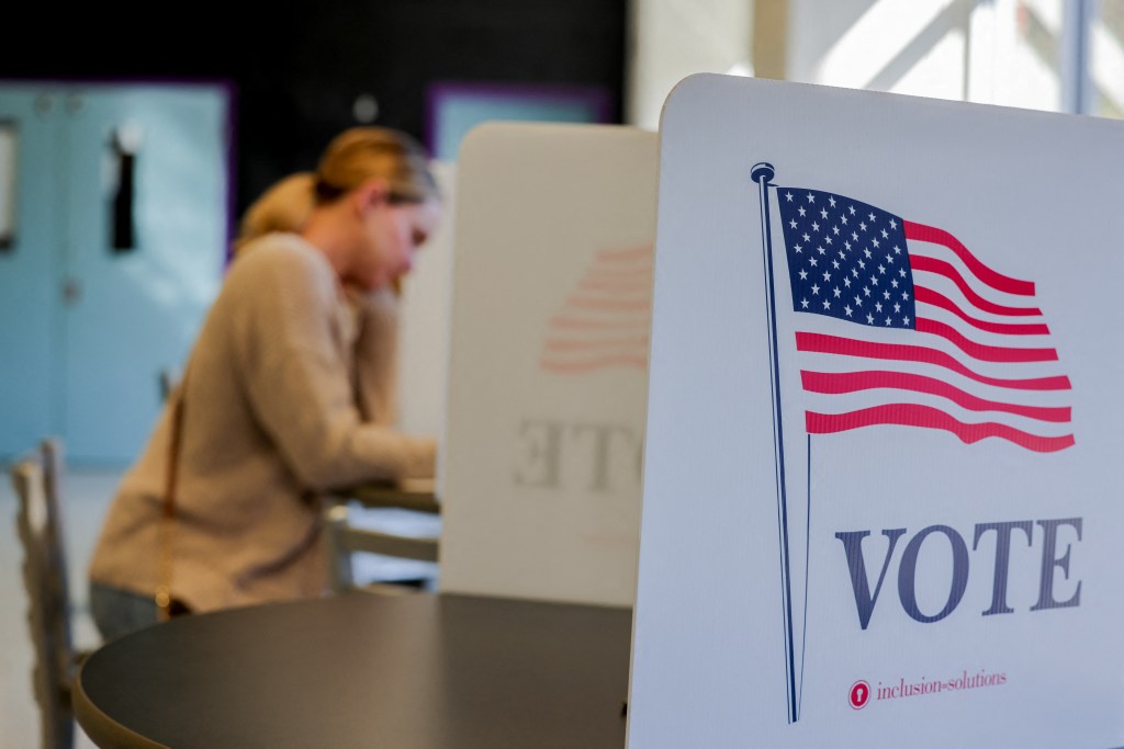 A woman fills out her ballot at a voting booth.